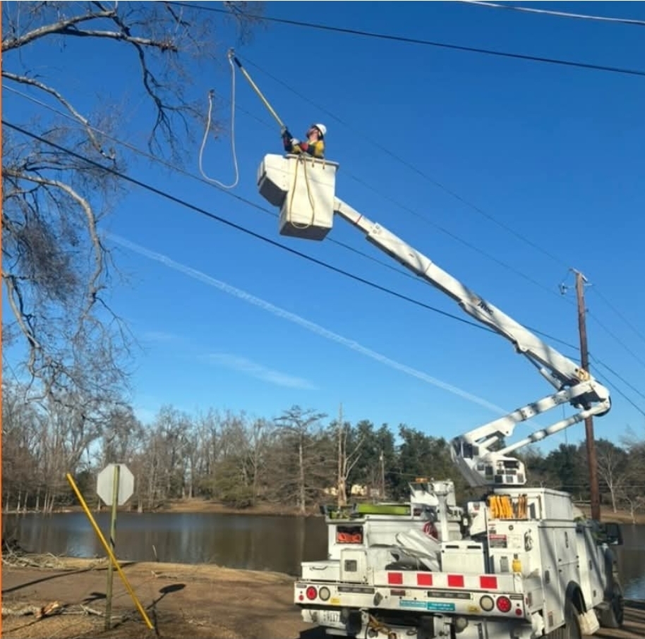 Lineman in a bucket truck working on power lines over a pond