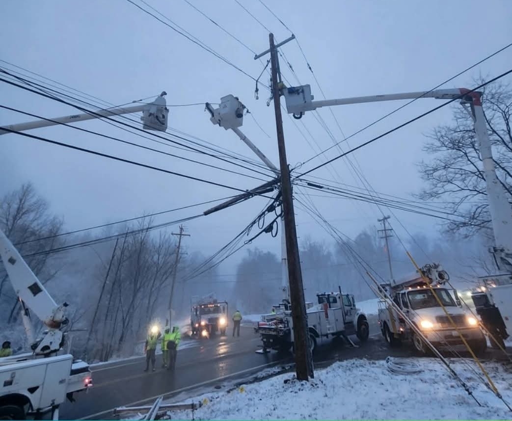Linemen working on tangled lines in foggy snowy weather with bucket trucks